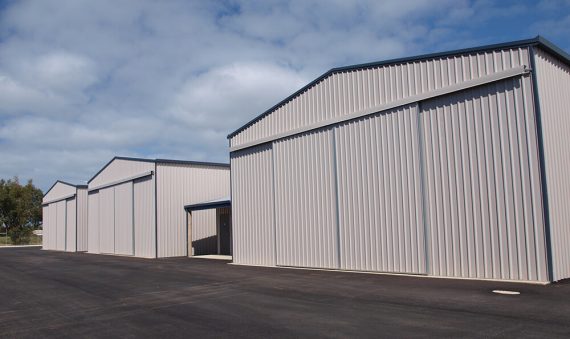 A row of three identical steel storage buildings with sliding doors, showing the modular options available from Industrial Shed Manufacturers in Pakistan like Steel City.