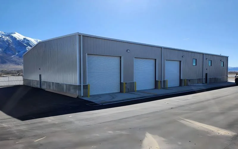 A modern grey pre-engineered metal building with roller shutter doors, showcasing durable structural work from Steel City, a provider among Industrial Shed Manufacturers in Pakistan.