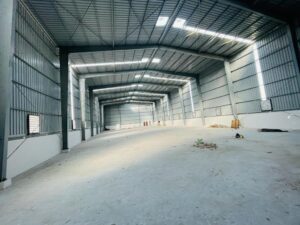 The spacious interior of an empty steel warehouse with a concrete floor, highlighting the clear-span design of Factory Sheds fabricated by Steel City.