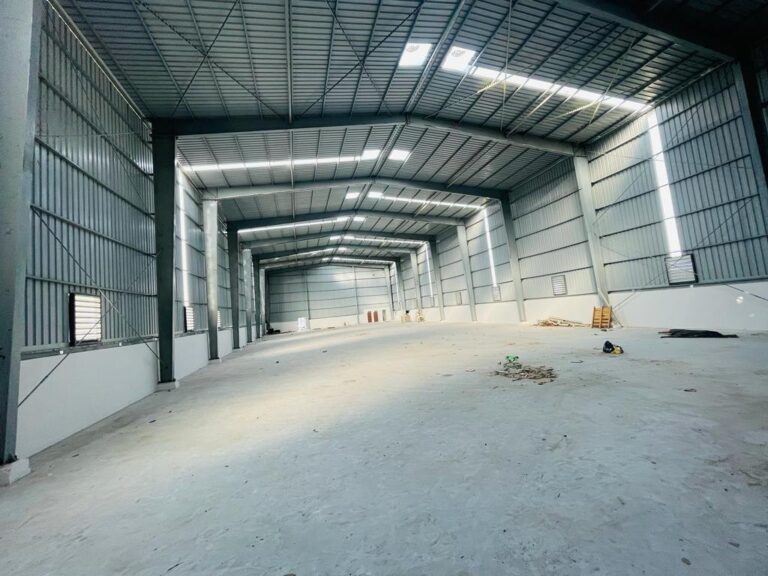 The spacious interior of an empty steel warehouse with a concrete floor, highlighting the clear-span design of Factory Sheds fabricated by Steel City.