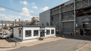 Exterior view of a modular factory site office cabin placed beside an industrial facility.